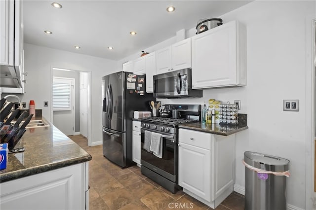 kitchen with white cabinetry, stainless steel appliances, sink, and dark stone countertops