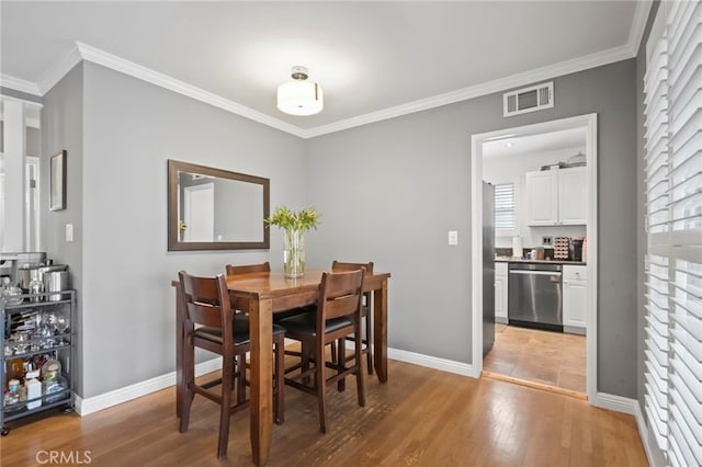 dining area featuring ornamental molding and light hardwood / wood-style floors