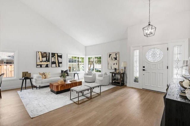 entryway featuring an inviting chandelier, high vaulted ceiling, and light wood-type flooring