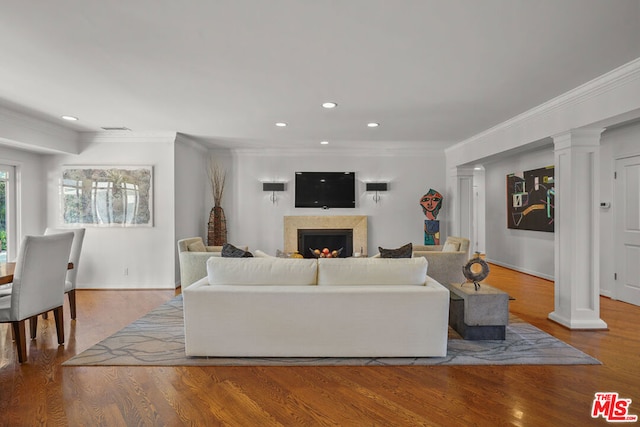 living room with decorative columns, hardwood / wood-style floors, and ornamental molding