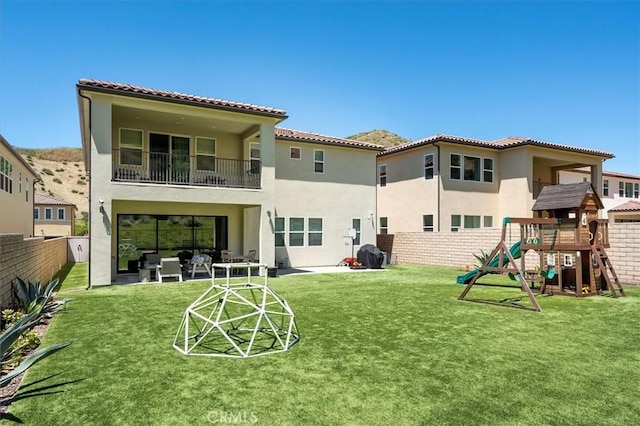 back of property with a yard, a patio area, and a playground