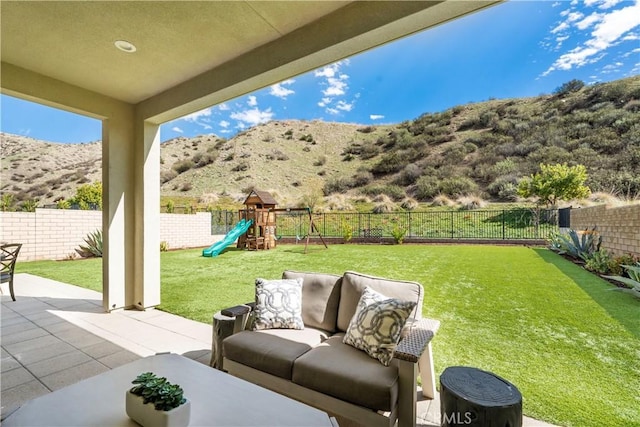 view of patio featuring a fenced backyard, a playground, an outdoor living space, and a mountain view