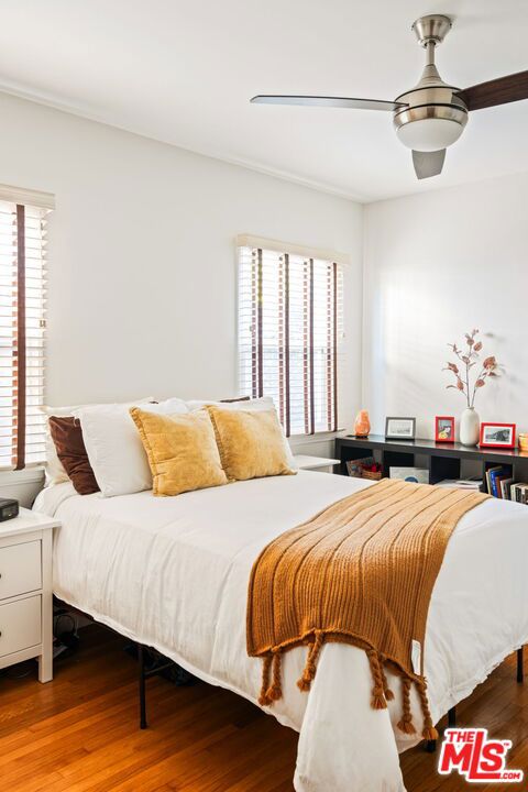 bedroom featuring multiple windows, hardwood / wood-style floors, and ceiling fan