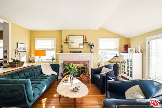 living room with lofted ceiling, hardwood / wood-style floors, and a brick fireplace