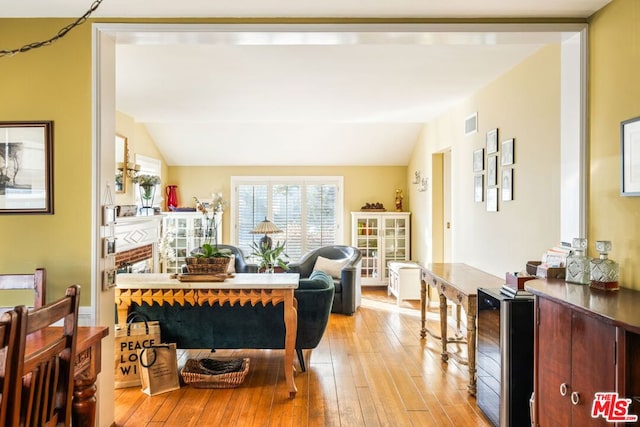 interior space with lofted ceiling, beverage cooler, and light wood-type flooring