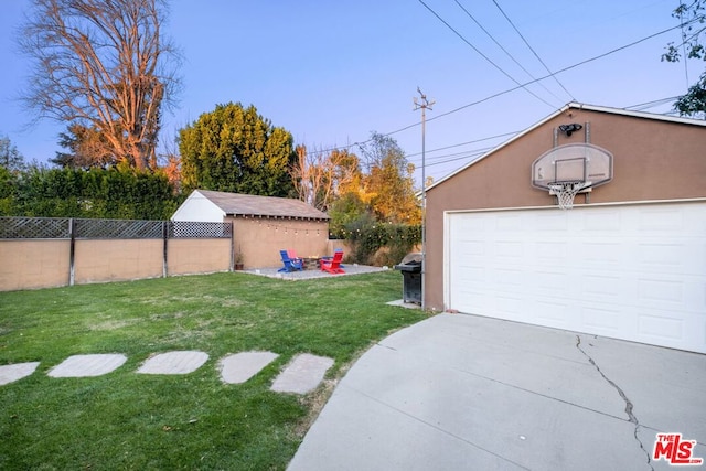 view of yard featuring a garage, an outbuilding, and a fire pit