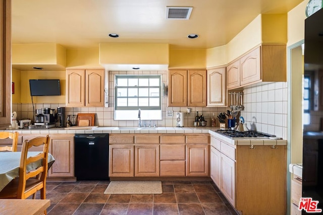 kitchen featuring stainless steel gas stovetop, backsplash, tile counters, and black dishwasher