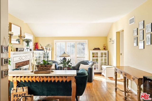 interior space with vaulted ceiling, a fireplace, and light hardwood / wood-style flooring