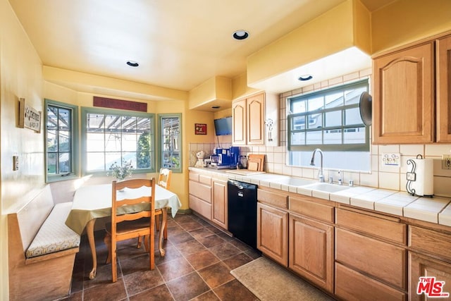 kitchen with sink, black dishwasher, tile counters, and decorative backsplash