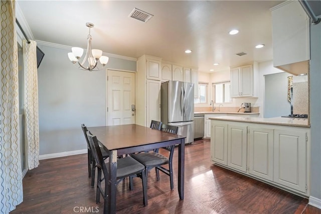 dining room featuring crown molding, sink, dark hardwood / wood-style floors, and an inviting chandelier