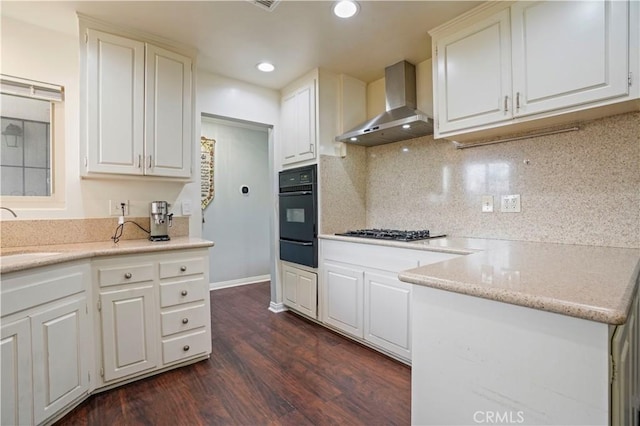 kitchen featuring white cabinets, dark wood-type flooring, wall chimney range hood, oven, and stainless steel gas stovetop