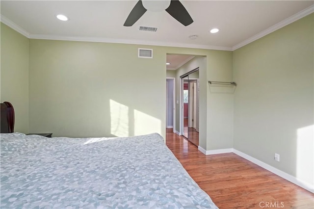 bedroom featuring ceiling fan, wood-type flooring, a closet, and ornamental molding