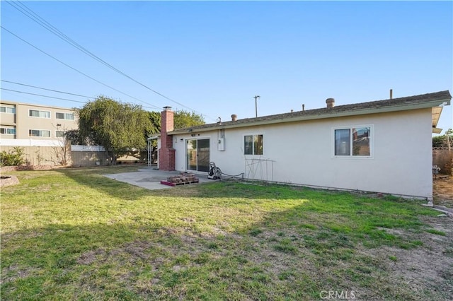 rear view of property featuring a patio and a lawn