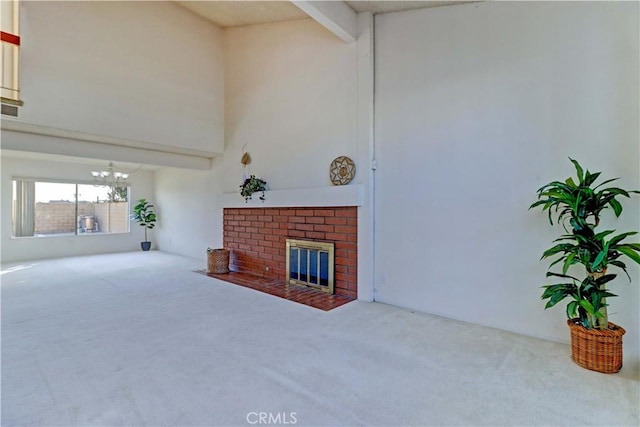 living room with a high ceiling, carpet floors, beamed ceiling, an inviting chandelier, and a brick fireplace