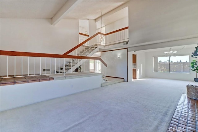 unfurnished living room featuring beamed ceiling, an inviting chandelier, carpet, and high vaulted ceiling