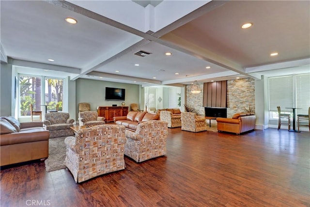 living room with dark hardwood / wood-style floors, beam ceiling, and a stone fireplace