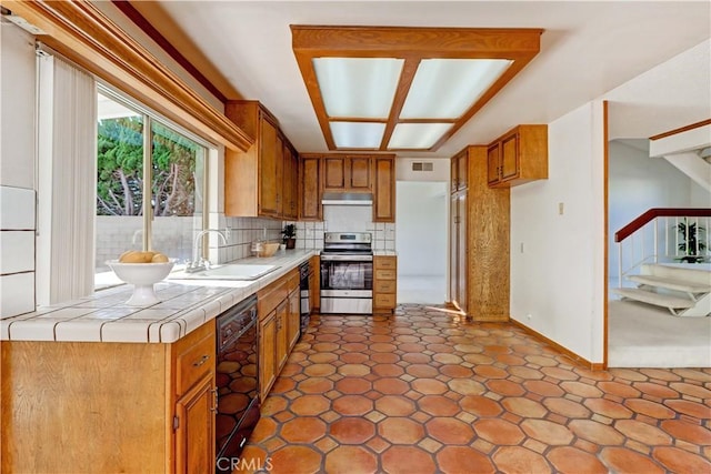 kitchen with tile counters, black dishwasher, decorative backsplash, sink, and stainless steel electric range