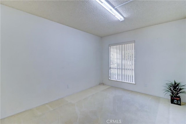 carpeted empty room featuring a textured ceiling