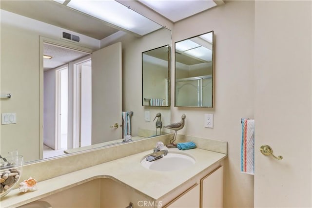 bathroom featuring a shower with door and vanity