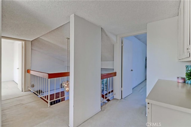 hallway featuring a textured ceiling and light carpet