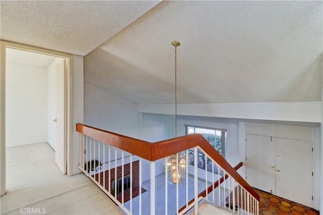 stairway featuring a textured ceiling and lofted ceiling