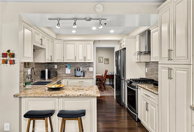 kitchen featuring refrigerator, light stone countertops, decorative backsplash, kitchen peninsula, and stainless steel gas stove