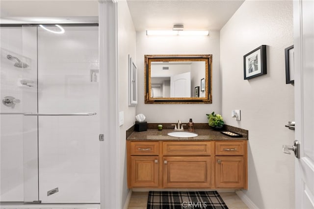 bathroom with a shower with shower door, tile patterned floors, and vanity