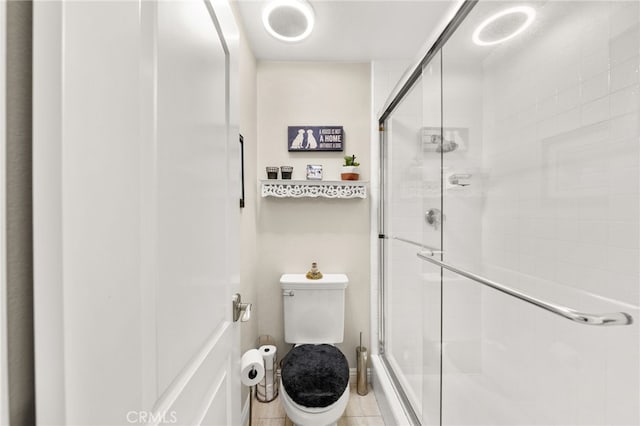 bathroom featuring toilet, tile patterned floors, and a shower with shower door