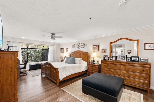 bedroom featuring ceiling fan, ornamental molding, hardwood / wood-style floors, and a textured ceiling