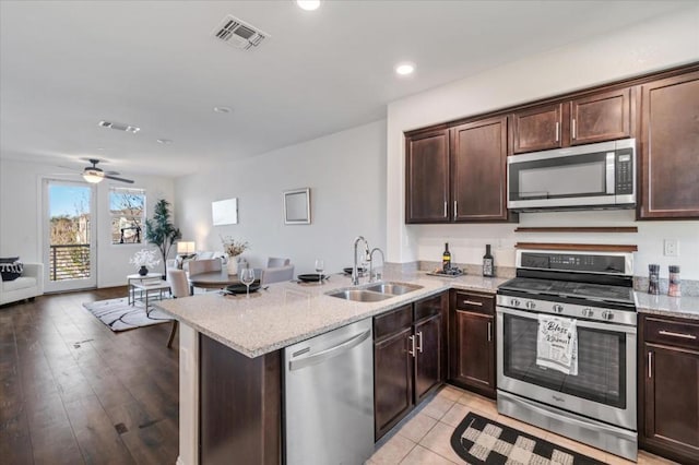 kitchen featuring dark brown cabinetry, stainless steel appliances, kitchen peninsula, and sink