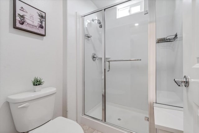 bathroom featuring toilet and a shower with door