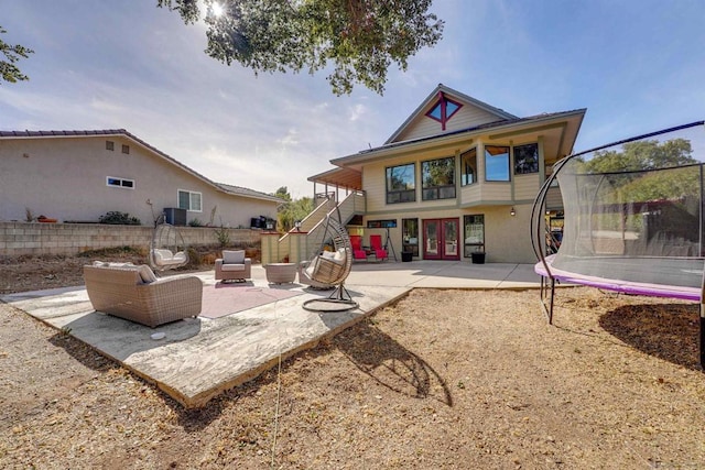 back of house with an outdoor living space, a patio, a trampoline, and central AC