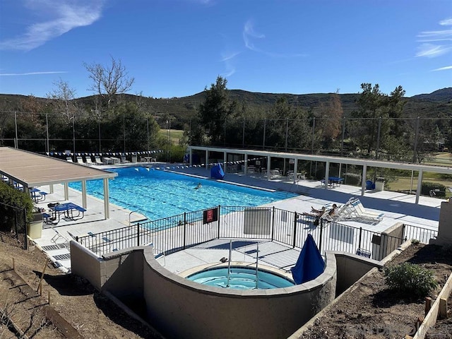 view of swimming pool featuring a community hot tub, a mountain view, and a patio