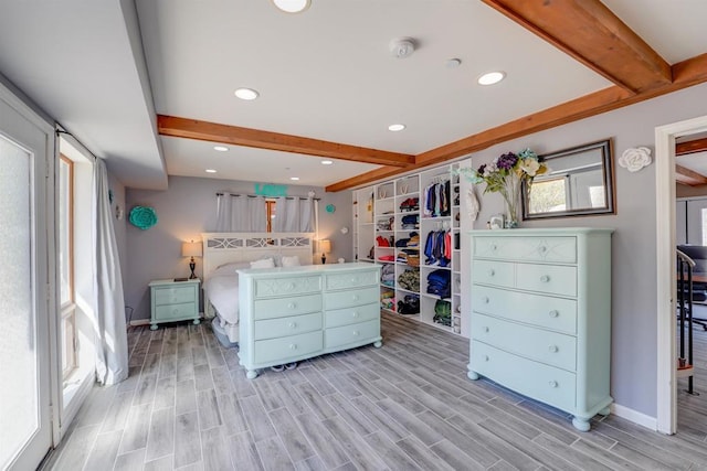 bedroom featuring a closet, beam ceiling, and light wood-type flooring