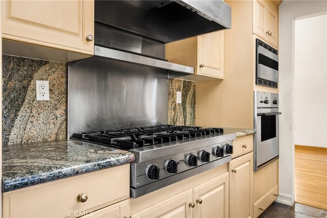 kitchen featuring backsplash, ventilation hood, dark stone countertops, and stainless steel appliances