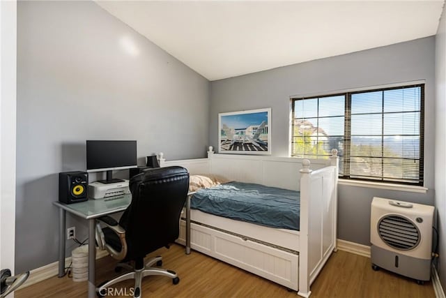 bedroom featuring heating unit, hardwood / wood-style floors, and lofted ceiling