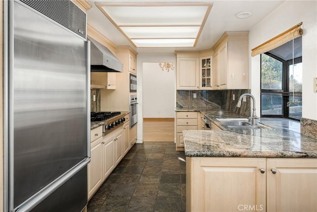 kitchen featuring appliances with stainless steel finishes, tasteful backsplash, hanging light fixtures, sink, and dark stone counters