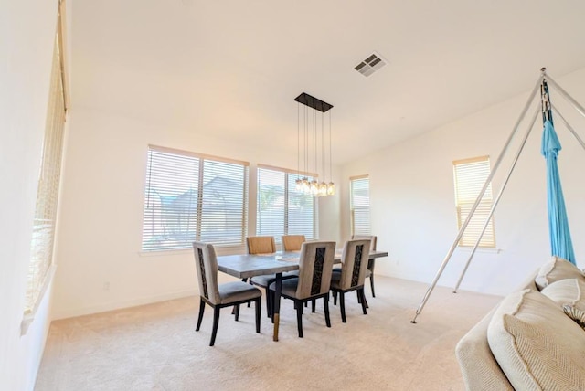 carpeted dining space with lofted ceiling and a chandelier