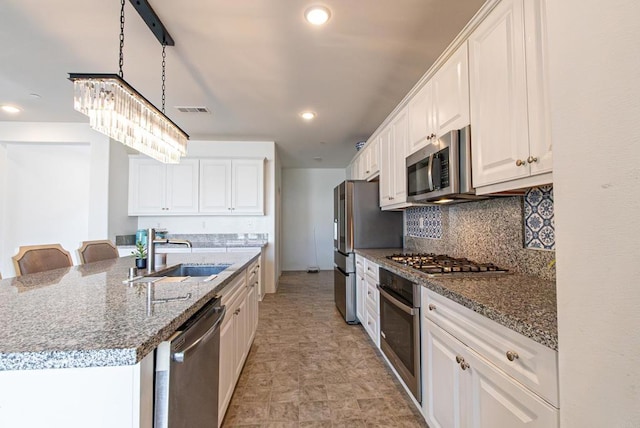 kitchen featuring sink, white cabinetry, tasteful backsplash, stone counters, and stainless steel appliances