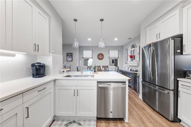 kitchen featuring sink, decorative light fixtures, white cabinets, tasteful backsplash, and stainless steel appliances