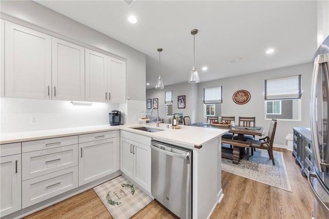 kitchen featuring sink, stainless steel appliances, white cabinets, and kitchen peninsula