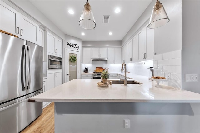 kitchen with decorative light fixtures, white cabinetry, kitchen peninsula, and stainless steel appliances