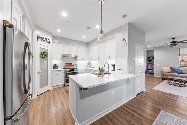 kitchen with sink, decorative light fixtures, white cabinets, tasteful backsplash, and stainless steel appliances