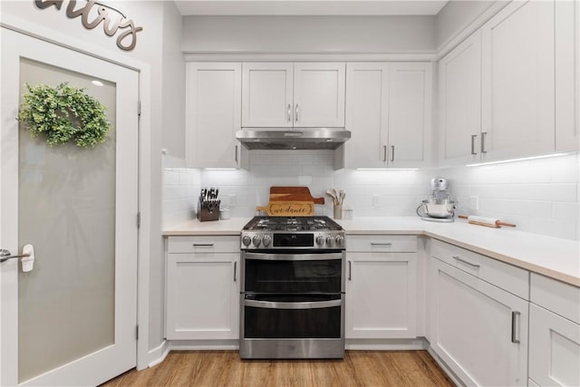 kitchen featuring white cabinets, double oven range, light hardwood / wood-style floors, and tasteful backsplash