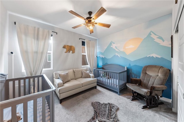 bedroom with ceiling fan, carpet, and a crib