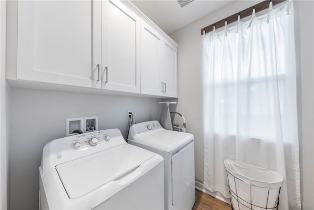 laundry area with dark wood-type flooring, cabinets, and independent washer and dryer