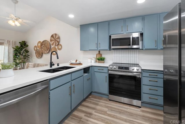 kitchen with light hardwood / wood-style floors, sink, blue cabinets, backsplash, and stainless steel appliances