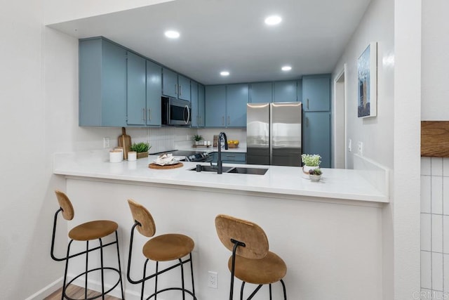 kitchen featuring sink, kitchen peninsula, stainless steel appliances, and blue cabinets