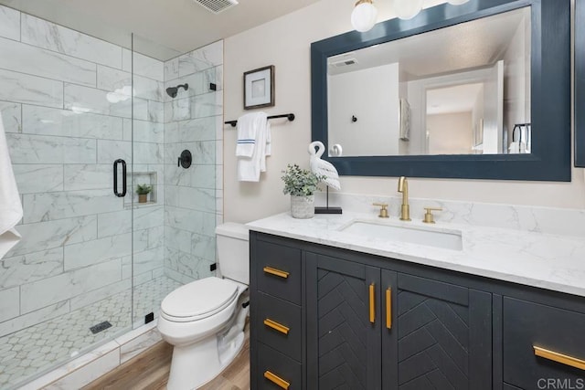 bathroom with wood-type flooring, an enclosed shower, vanity, and toilet