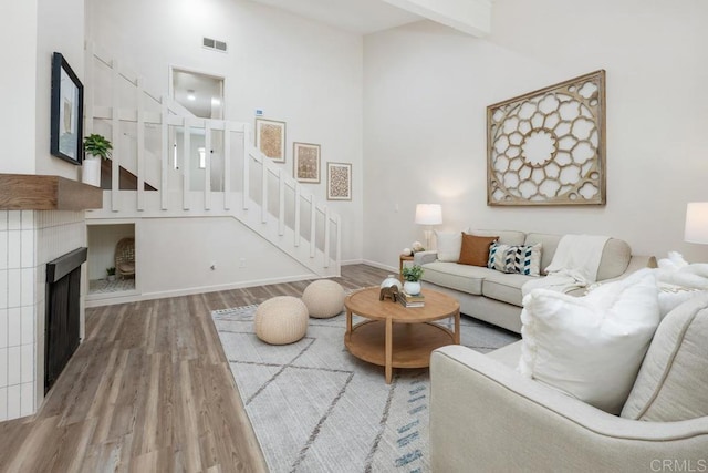 living room featuring a tiled fireplace, hardwood / wood-style flooring, and a high ceiling